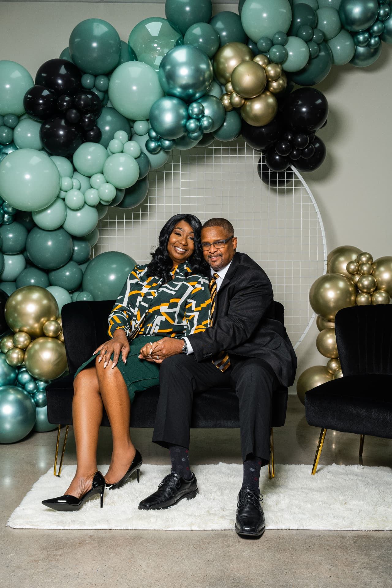 Two people seated beneath the Get It Poppin balloon installation