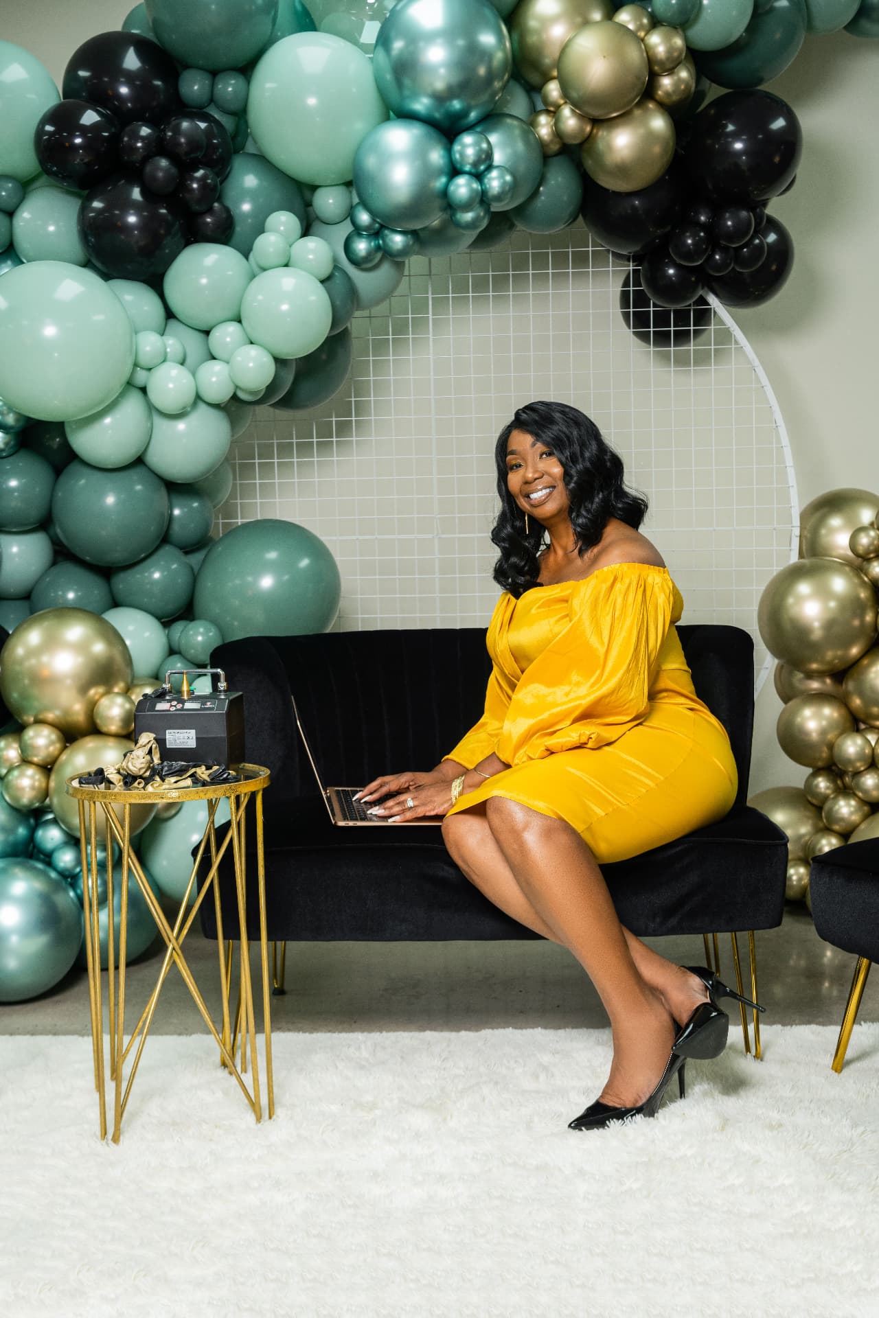 Seated brand portrait with balloon decor and gold display tables