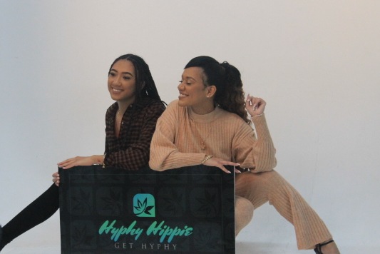 The Hyphy Hippie owners holding their brand sign on set in the studio